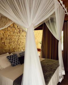 um quarto com uma cama de dossel branca com cortinas em Quinta da Bocaina em Amparo