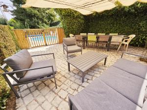 eine Terrasse mit einem Tisch, Stühlen und einem Sonnenschirm in der Unterkunft Gîte Le creux du loup in La Couronne