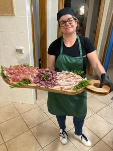 a woman holding a tray of meat on a board at Agriturismo Sa Mandria in Castiadas