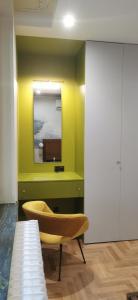 une chambre jaune avec un miroir et une chaise dans l'établissement Rudy Kot, à Gdańsk
