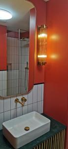 La salle de bains est pourvue d'un lavabo blanc et d'un miroir. dans l'établissement Rudy Kot, à Gdańsk