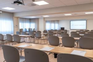 a room with tables and chairs and a projection screen at Maritim Fjordhotel in Flekkefjord