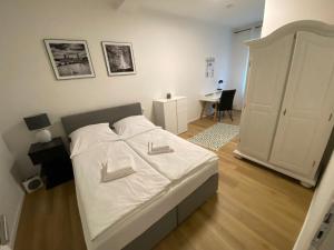 um quarto com uma cama com lençóis brancos e uma secretária em Swan Rooms em Nurembergue