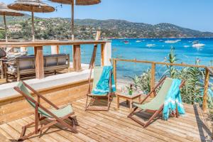 a deck with chairs and umbrellas and the ocean at Akwabay - Les Villas du Cap in Le Lavandou