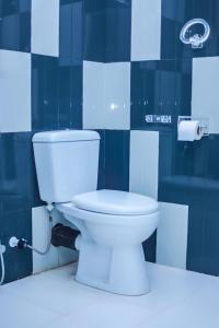 a white toilet in a bathroom with blue tiles at Royal Hub in Negombo