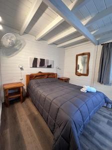 um quarto com uma cama grande e um cobertor azul em Portal del Manzano em Villa La Angostura