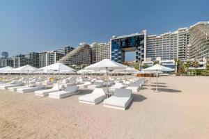a beach with white lounge chairs and umbrellas at Manzil - Lavish 2BR Sea View Apartment in Five Palm, Palm Jumeirah in Dubai