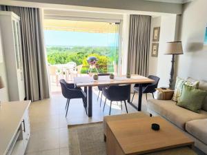 a living room with a table and a couch at Sara's Upmarket Apartment - Lagoon Views, Patio, Braai & WIFI & DSTV in Plettenberg Bay