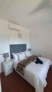 1 dormitorio con 1 cama grande con sábanas y almohadas blancas en Ocean Walk Marlin, en Zinkwazi Beach