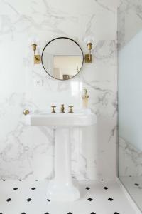 a white bathroom with a sink and a mirror at Château De La Bûcherie in Saint-Cyr-en-Arthies