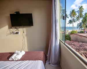 um quarto com uma televisão, uma cama e uma janela em Cocco Pousada em Maragogi