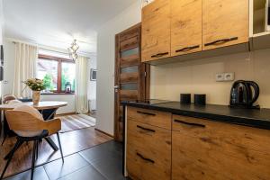 a kitchen with wooden cabinets and a table in a room at Apartament Aparteo E7 in Kościelisko