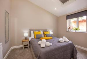 um quarto com uma cama com almofadas amarelas e cinzentas em Hollis House York- 4 bedroom with free parking em Strensall