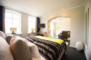 ein Schlafzimmer mit einem Bett, einem Sofa und einem Spiegel in der Unterkunft Hotel Hof Galerie in Morsum