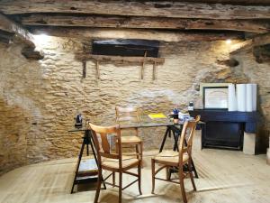 ein Zimmer mit einem Tisch und Stühlen in einer Steinmauer in der Unterkunft Gîte la Borie du bois Sarlat in Saint-André-dʼAllas