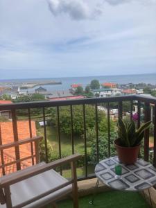 a balcony with a chair and a table and the ocean at La Casa del Gallo in Luanco