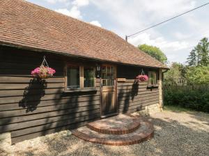 uma pequena casa com uma porta e flores nela em Bolton Barn em Lenham