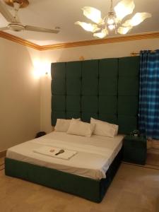 a bedroom with a large bed with a green headboard at Johar Hill view Guest House in Karachi