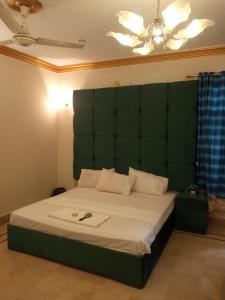 a bedroom with a large bed with a green headboard at Johar Hill view Guest House in Karachi