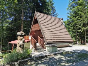 a log cabin with a red roof and a porch at KOČA PLANIKA, SVIŠČAKI in Ilirska Bistrica