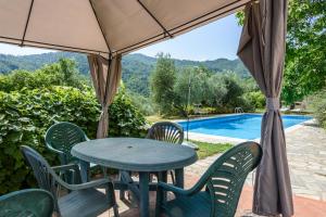 a table and chairs under an umbrella next to a swimming pool at Villa Feraldi in Scopeti