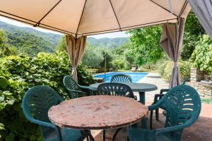 a table and chairs under an umbrella next to a pool at Villa Feraldi in Scopeti