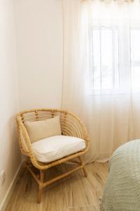 silla de mimbre en una habitación con ventana en Nōhō house, en Carrapateira