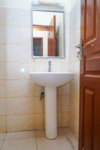 y baño con lavabo blanco y espejo. en Lux Suites Greatwall Getaway Apartments en Machakos