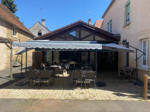 a patio with tables and chairs and an umbrella at hotel du commerce in Joncy