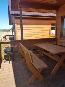 a picnic table and a grill on the back porch of a cabin at Dolina Rusinowa in Rusinowo