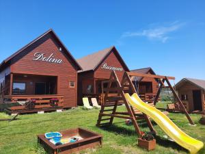 a log cabin with a slide and a playground at Dolina Rusinowa in Rusinowo