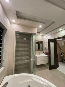 een badkamer met een bad, een douche en een wastafel bij Stylish Vacation Home in DHA near Airport in Lahore