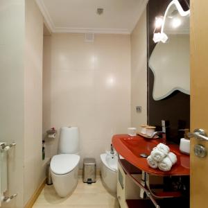 a bathroom with a white toilet and a red counter at Acogedor ático en Salamanca by beBalmy in Salamanca