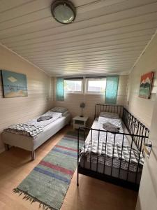 two beds in a room with two windows at Midnattsolveien 3158,Sommarhusstrand in Laukvik
