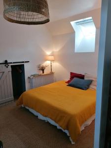 - une chambre avec un grand lit et une couverture jaune dans l'établissement La Robinière Maison d'Hôtes, à Mont-près-Chambord