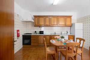 a kitchen with wooden cabinets and a table with chairs at Quinta Alegre Tavira T2 in Luz de Tavira