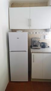 a kitchen with white cabinets and a white refrigerator at Ocean Walk Manta in Zinkwazi Beach