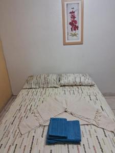 a bed with two blue items sitting on it at POUSADA AMAZONAS in Rio das Ostras