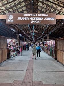 リオ・ダス・オストラスにあるPOUSADA AMAZONASの看板を持って市場を歩く女