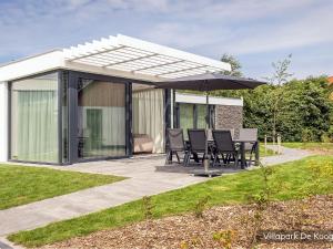 a pavilion with chairs and an umbrella on a patio at Villa in Texel near De Koog Beach in De Koog