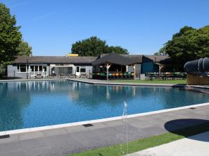 a large swimming pool in front of a building at Chalet with Pond View in Gelderland in Lathum