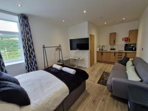 a bedroom with a bed and a couch and a kitchen at Apartment 4 Tynte Hotel. Mountain Ash. Just a short drive to Bike Park Wales in Quakers Yard