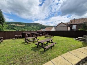 a group of picnic tables in a yard with a fence at Apartment 4 Tynte Hotel. Mountain Ash. Just a short drive to Bike Park Wales in Quakers Yard