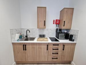 a kitchen with wooden cabinets and a sink at Apartment 4 Tynte Hotel. Mountain Ash. Just a short drive to Bike Park Wales in Quakers Yard
