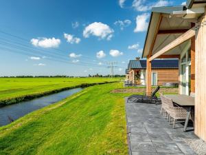 eine Terrasse mit einem Tisch und Stühlen neben einem Fluss in der Unterkunft Beautiful group accommodation with wellness, on a holiday park in Friesland in Akkrum