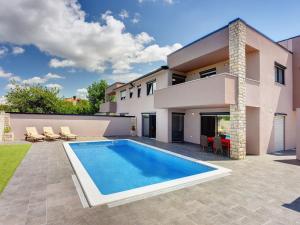 a villa with a swimming pool in front of a house at Luxury villa with private pool, terrace and BBQ in Valbandon