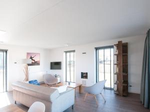 een woonkamer met een bank en stoelen bij Modern design lodge with combi microwave, in national park in Tholen