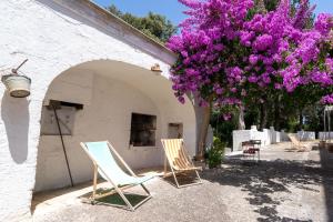 um grupo de cadeiras e uma árvore com flores roxas em Villa Boschetti Apartments em Monopoli