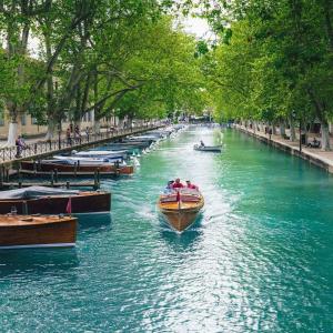 un groupe de bateaux naviguant sur une rivière avec des arbres dans l'établissement L Ecrin L4 3 min centre balcon, à Annecy