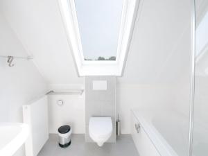 a bathroom with a white toilet and a skylight at Modern design lodge with combi microwave, in national park in Tholen